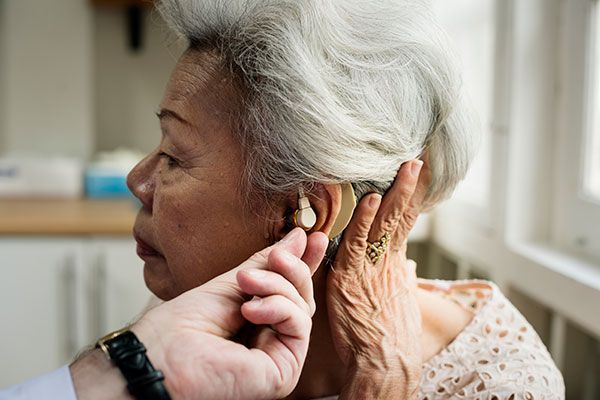 Elderly woman with a hearing aid being fitted on her