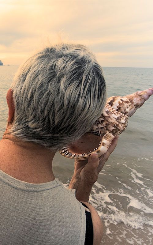 Woman listening to a big conch